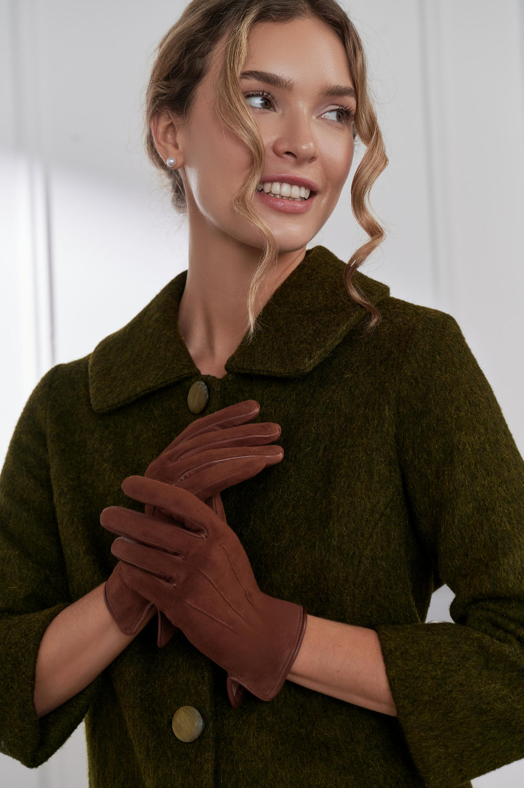 Woman wearing a green coat and brown gloves against a white background