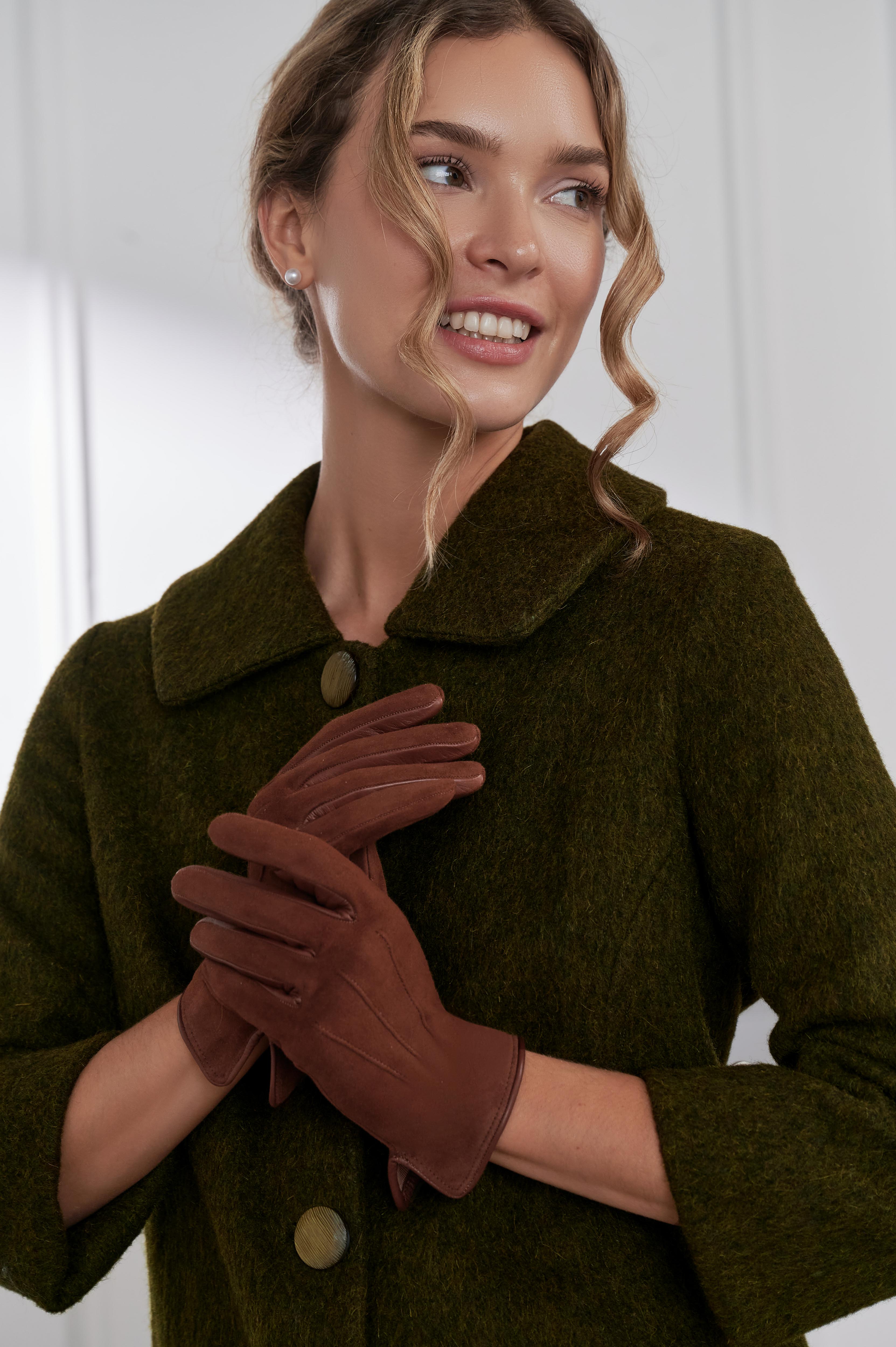 Woman wearing a green coat and brown gloves against a white background